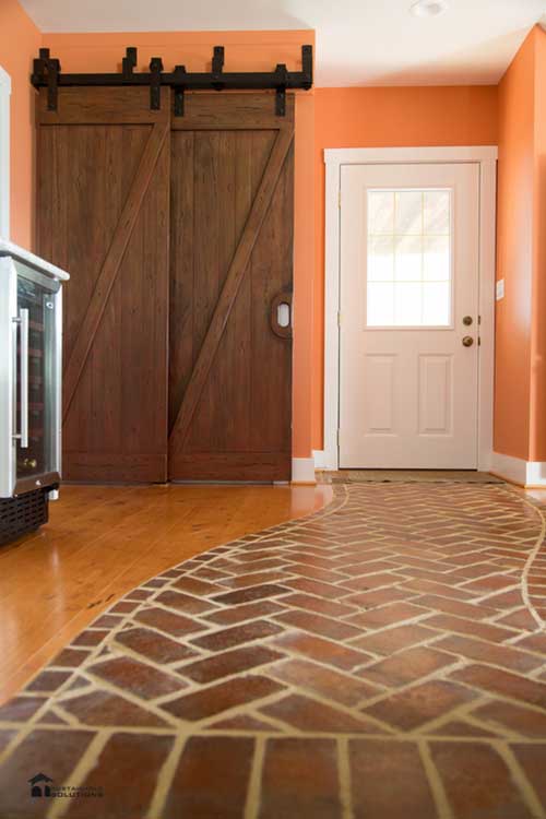 Red brick and hardwood floor with sliding wooden barn doors in kitchen