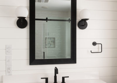 Bathroom vanity with reflection of tiled shower in mirror