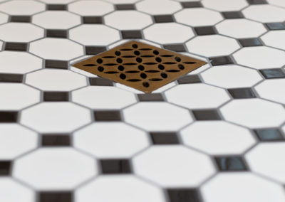 Detailed shot of tiled shower floors and patterned drain cover