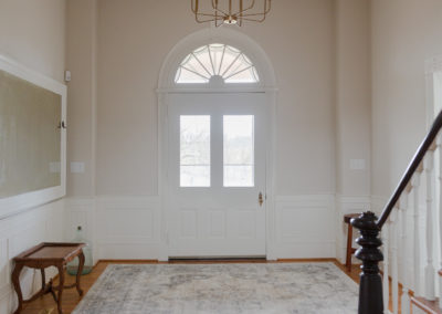 Entryway to farmhouse with a half round window above doorway